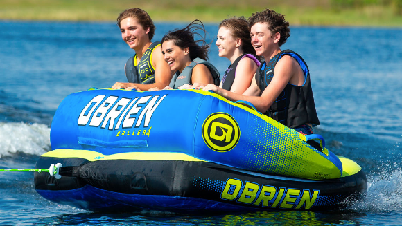 Image with 4 happy teens riding an Obrien tube which is blue and green 